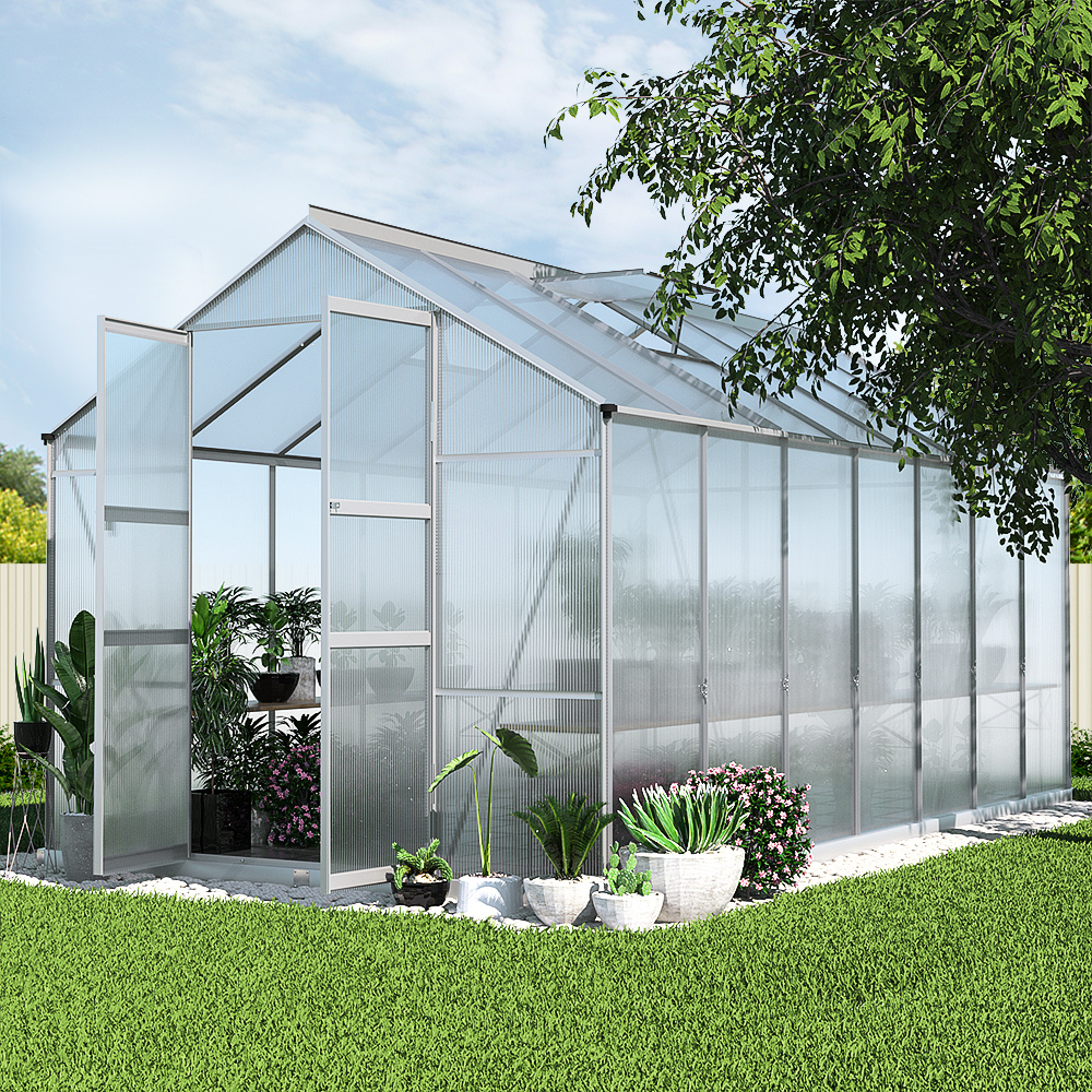 Greenhouse with plants on a grassy area under a clear sky