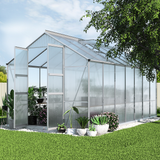 Greenhouse with plants on a grassy area under a clear sky
