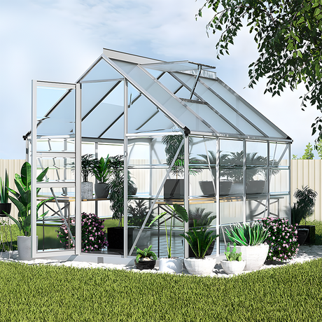 An outdoor setting featuring the aluminium polycarbonate greenhouse filled with plants and potted flowers, surrounded by a well-maintained garden