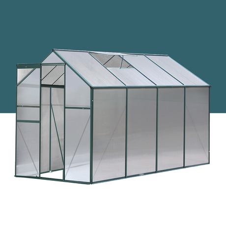 A rendered 3D illustration of a greenhouse, featuring a pitched roof and clear panels, with a dark green frame set against a plain blue-gray background.