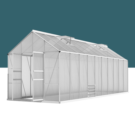 A large, walk-in greenhouse made of transparent polycarbonate panels with an aluminium frame, featuring a sloped roof and double door entrance