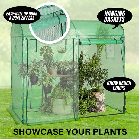 A green dome greenhouse designed for showcasing plants, featuring an easy-roll-up door with dual zippers for convenient access. The image highlights its capability to accommodate hanging baskets and grow bench crops, showcasing potted plants, hanging foliage, and lush greenery inside. The sturdy PE cover ensures ample sunlight penetration while protecting plants from external elements. The greenhouse is presented outdoors, blending practicality with aesthetic appeal for gardening enthusiasts.