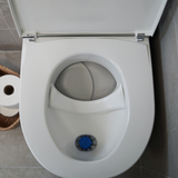 White Separett Tiny® Composting Toilet With Urine Tube with open lid in a bathroom setting