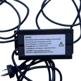 A black power adapter unit is shown with cables, featuring a warning label about connection order and surge protection requirements.