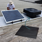 Person installing a solar panel on a roof with a black exhaust fan in the background.