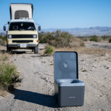 Trelino® Evo Portable Composting Toilet on a gravel road with a camper van in the background.