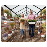 Man and woman walking through a greenhouse filled with plants and flowers.