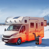 White and orange RV parked in a snowy landscape with mountains in the background